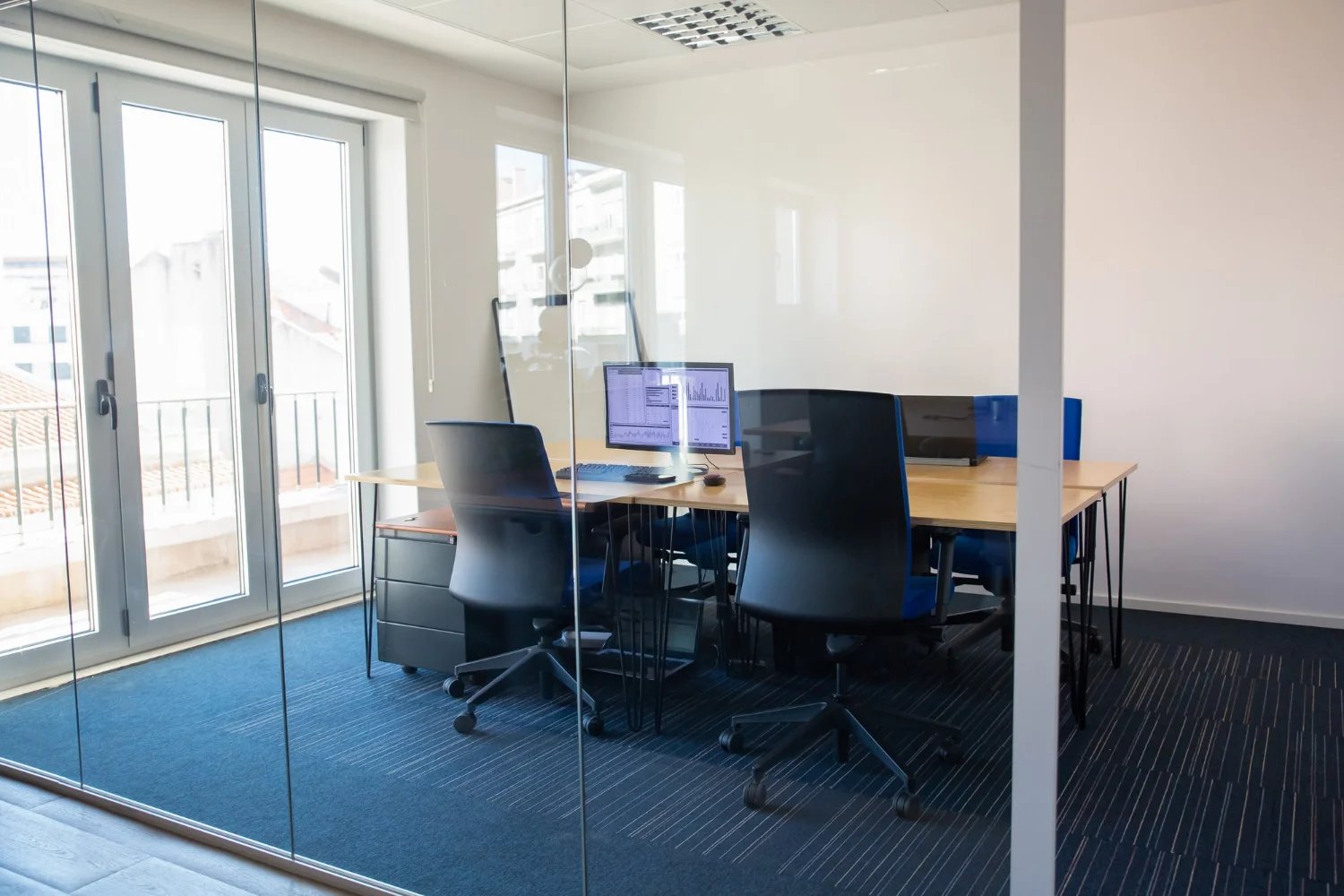 empty-boardroom-glass-wall-meeting-room-with-conference-table-shared-desk-team-workplaces-trading-graphs-monitor-office-interior-commercial-real-estate-concept