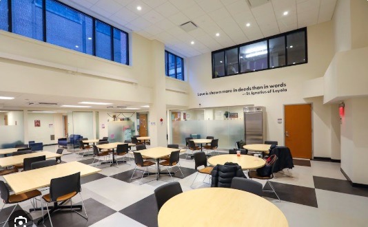 Loyola High School learning space with tables, seating, and wall-mounted display